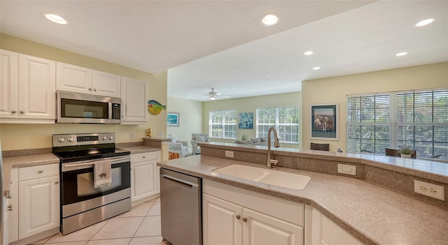 kitchen featuring appliances with stainless steel finishes, white cabinets, sink, ceiling fan, and light tile floors