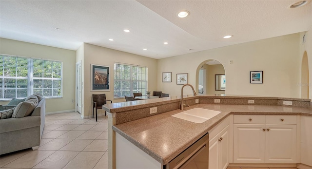 kitchen with a healthy amount of sunlight, dishwasher, light tile flooring, and sink