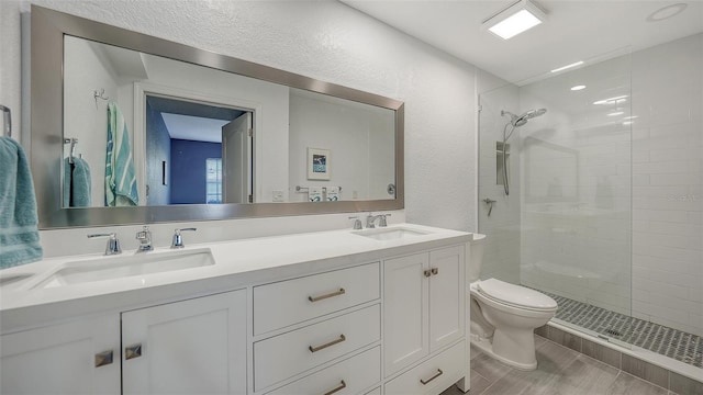 bathroom with a shower with shower door, double vanity, and toilet