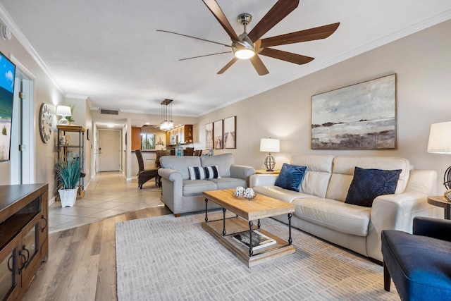 tiled living room with ceiling fan and crown molding