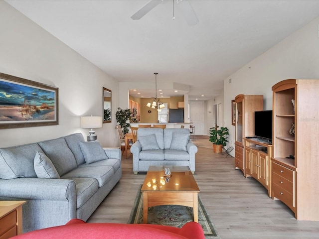 living room with ceiling fan with notable chandelier and light wood-type flooring