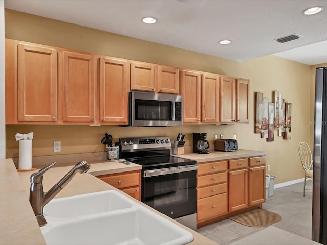 kitchen featuring light brown cabinetry, light tile patterned floors, sink, and appliances with stainless steel finishes