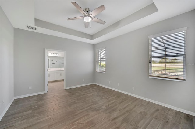 spare room featuring ceiling fan, a raised ceiling, and hardwood / wood-style floors