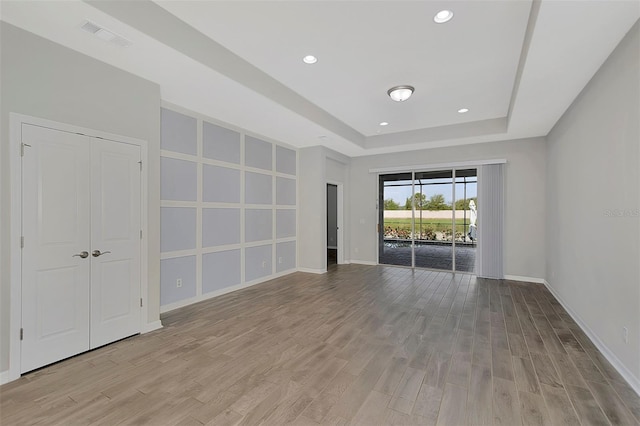 unfurnished room featuring light hardwood / wood-style floors and a tray ceiling