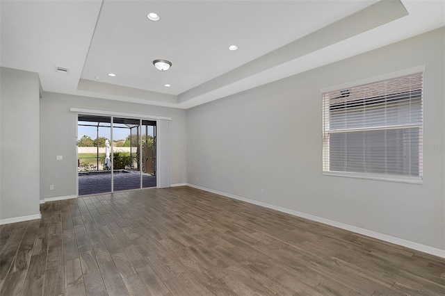 spare room with hardwood / wood-style flooring and a tray ceiling