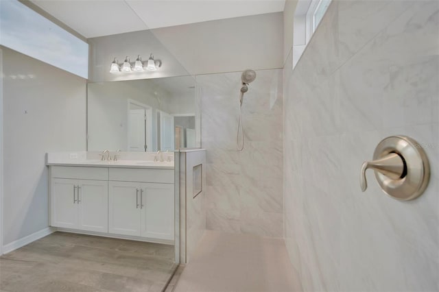 bathroom with a tile shower, vanity, and wood-type flooring