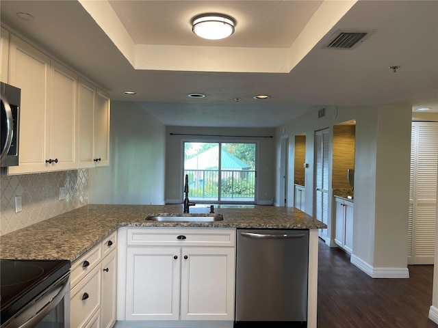 kitchen with stainless steel appliances, light stone counters, white cabinetry, and kitchen peninsula