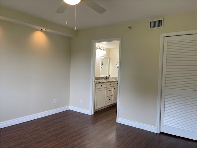 unfurnished bedroom with connected bathroom, a closet, ceiling fan, and dark hardwood / wood-style floors