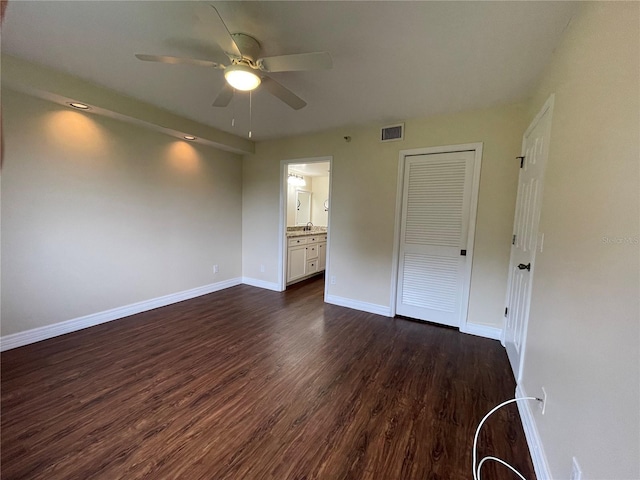 unfurnished bedroom with dark hardwood / wood-style floors, ceiling fan, a closet, and ensuite bath