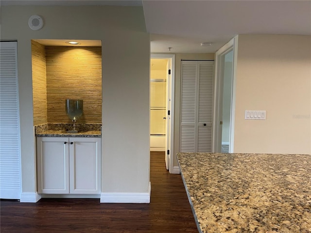 bar featuring white cabinets, stone counters, and dark hardwood / wood-style flooring