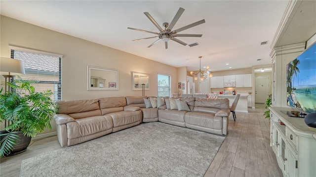 living room with ceiling fan with notable chandelier and light hardwood / wood-style flooring