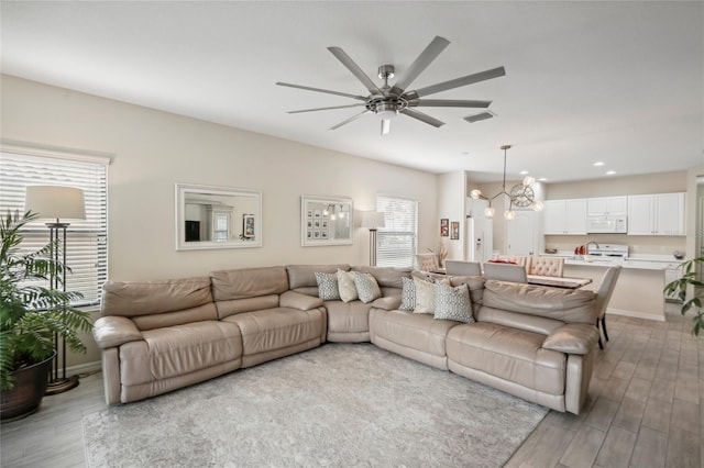 living room featuring light hardwood / wood-style floors and ceiling fan with notable chandelier