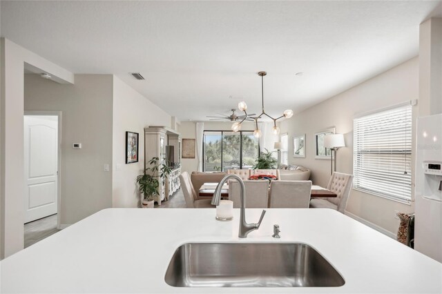 kitchen featuring pendant lighting, white refrigerator with ice dispenser, sink, and a wealth of natural light