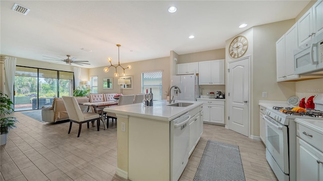 kitchen with white cabinets, a wealth of natural light, white appliances, and a kitchen island with sink