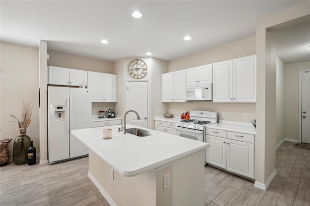 kitchen with white appliances, white cabinets, a center island with sink, sink, and light hardwood / wood-style floors