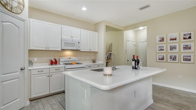 kitchen with white cabinetry, sink, an island with sink, white appliances, and light wood-type flooring