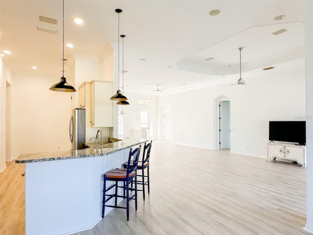 kitchen with arched walkways, hanging light fixtures, a ceiling fan, freestanding refrigerator, and open floor plan