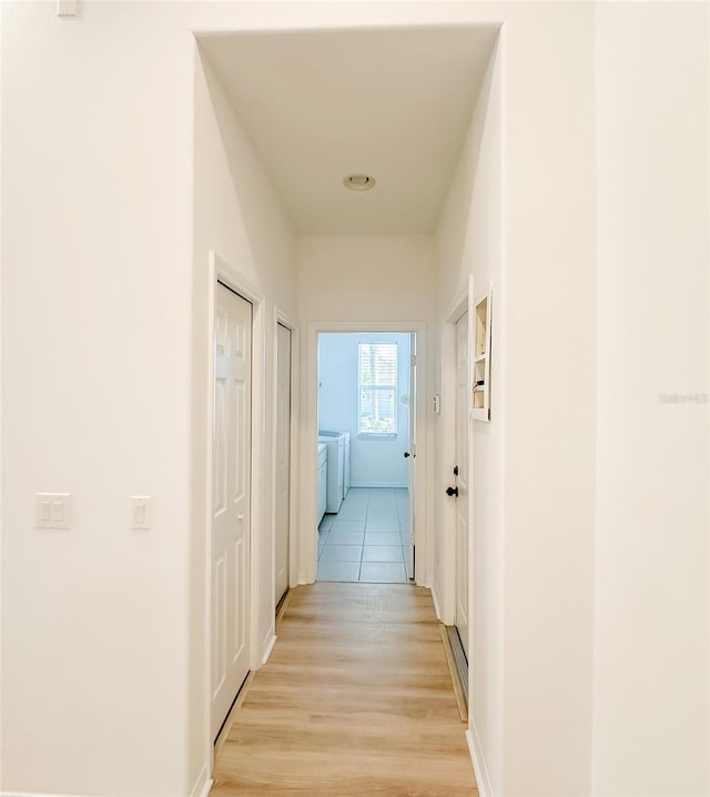 corridor featuring light wood finished floors and washing machine and clothes dryer