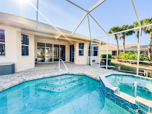 view of pool with glass enclosure, a pool with connected hot tub, and a patio