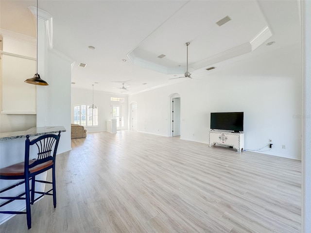 living room with arched walkways, a raised ceiling, a ceiling fan, and ornamental molding