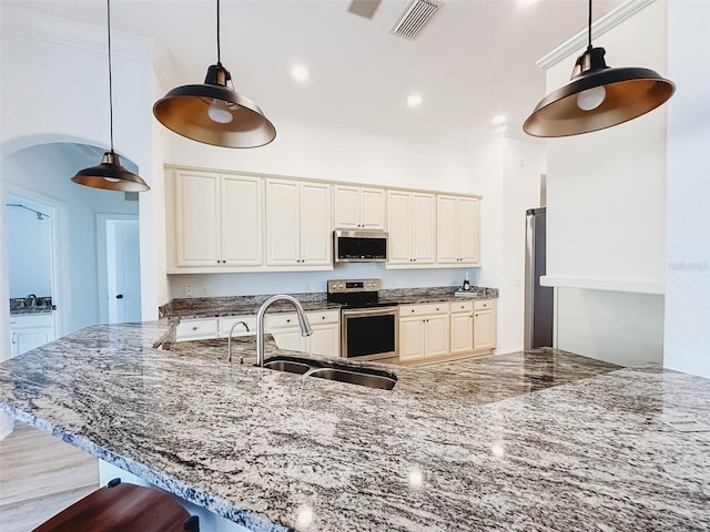 kitchen featuring a sink, a kitchen breakfast bar, hanging light fixtures, appliances with stainless steel finishes, and dark stone counters