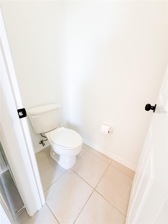 bathroom featuring tile patterned flooring, baseboards, and toilet