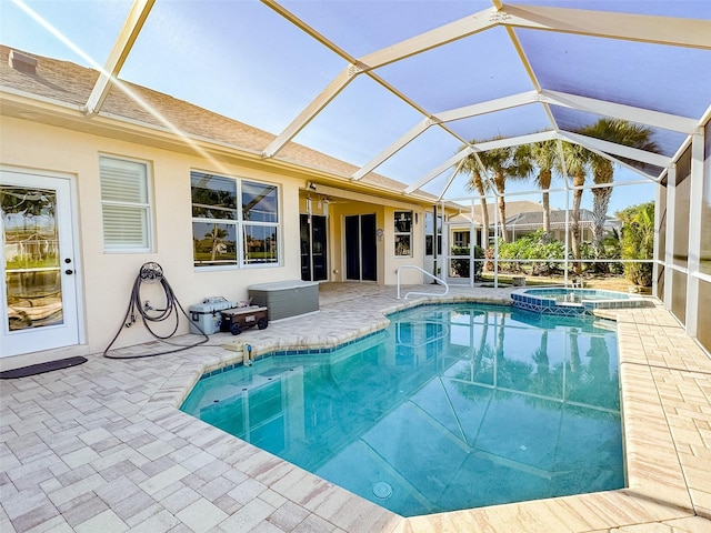 view of pool featuring a patio area, glass enclosure, and a pool with connected hot tub