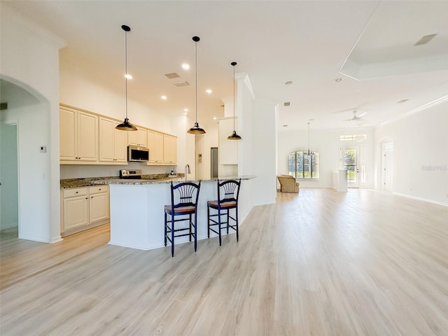 kitchen featuring arched walkways, pendant lighting, appliances with stainless steel finishes, open floor plan, and dark stone counters