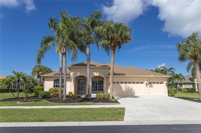 mediterranean / spanish-style house with a garage, concrete driveway, a front yard, and stucco siding