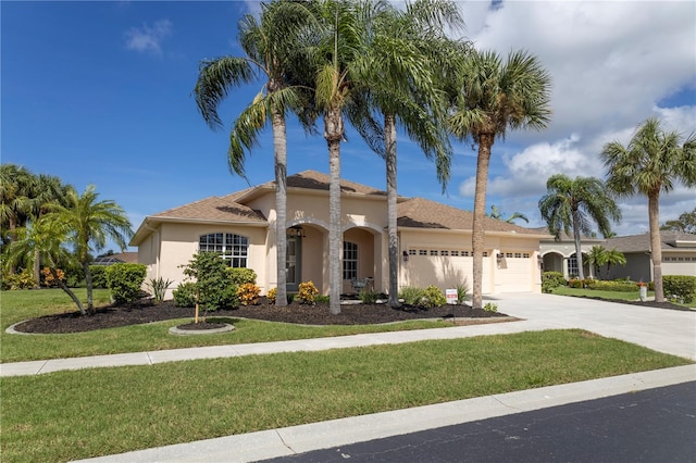 mediterranean / spanish-style home featuring a front yard, driveway, an attached garage, and stucco siding