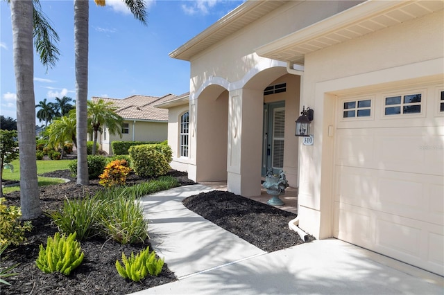 entrance to property featuring a garage and stucco siding