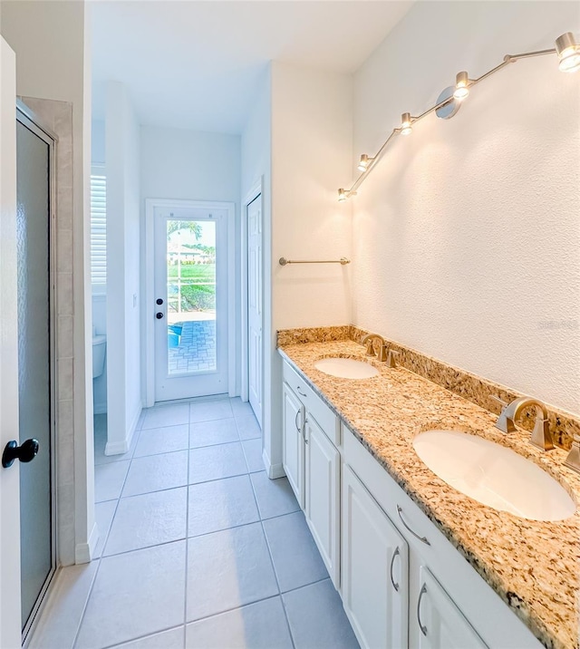 bathroom with toilet, tile patterned flooring, double vanity, and a sink