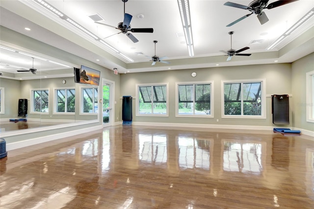 workout area with hardwood / wood-style floors, plenty of natural light, ceiling fan, and a raised ceiling