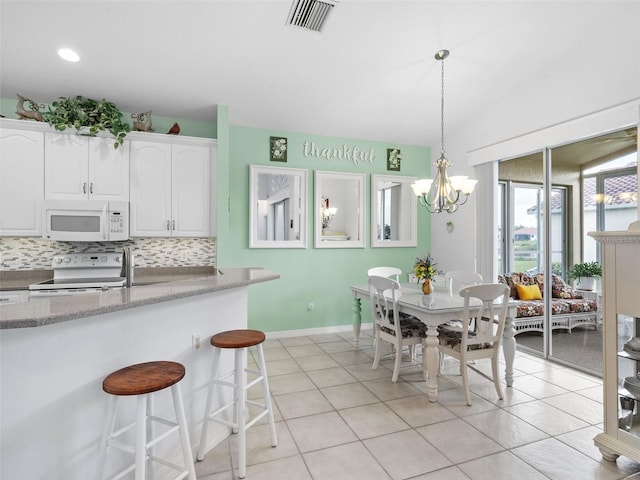 kitchen featuring white appliances, backsplash, white cabinets, hanging light fixtures, and a chandelier