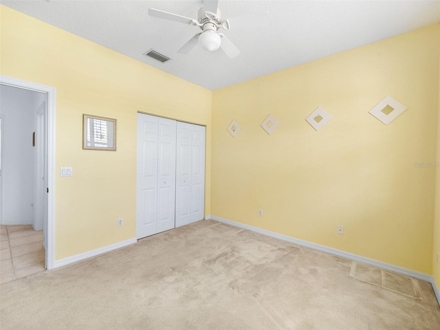 unfurnished bedroom with light carpet, a closet, and ceiling fan