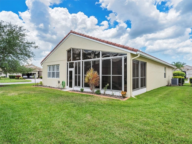 rear view of property with central AC, a sunroom, and a yard