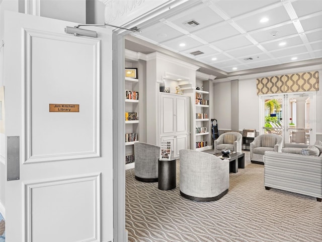 carpeted living room with built in shelves, ornamental molding, and coffered ceiling