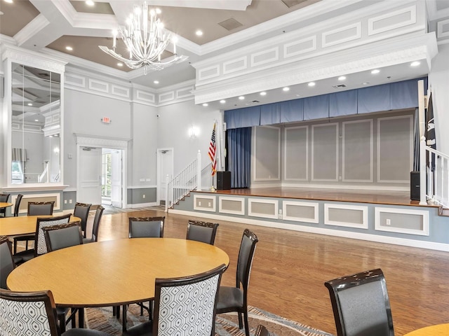 dining space featuring beam ceiling, coffered ceiling, a high ceiling, a chandelier, and ornamental molding