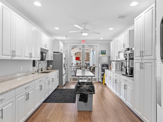 kitchen with light stone countertops, ceiling fan, sink, hardwood / wood-style flooring, and white cabinetry