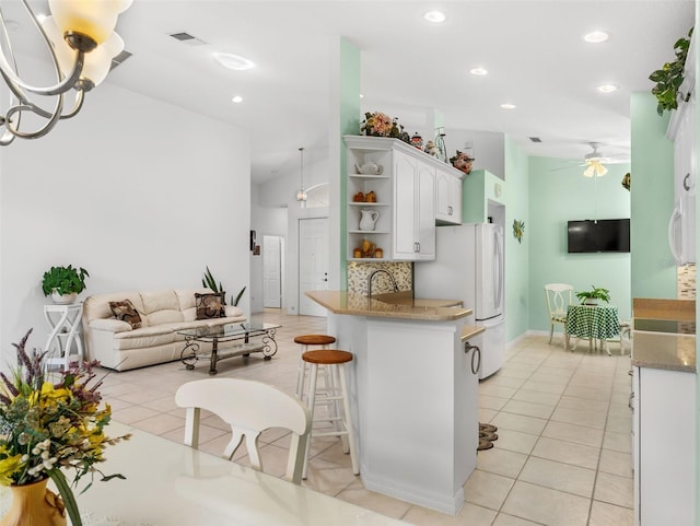 kitchen featuring backsplash, a kitchen breakfast bar, white refrigerator, kitchen peninsula, and white cabinetry