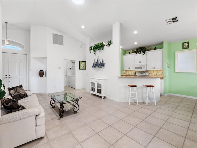 tiled living room featuring washer and dryer and high vaulted ceiling