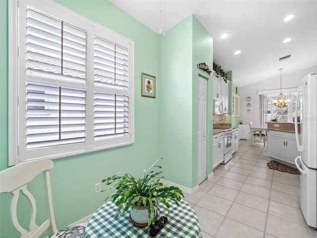 kitchen with light tile patterned flooring, decorative light fixtures, a chandelier, white appliances, and white cabinets