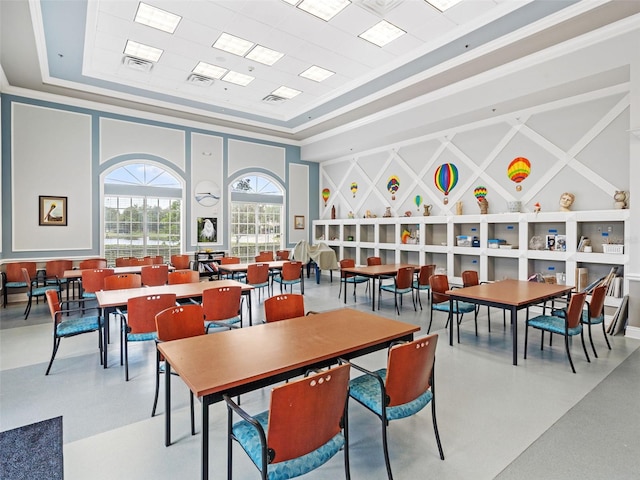 dining area with a tray ceiling, concrete floors, and a high ceiling