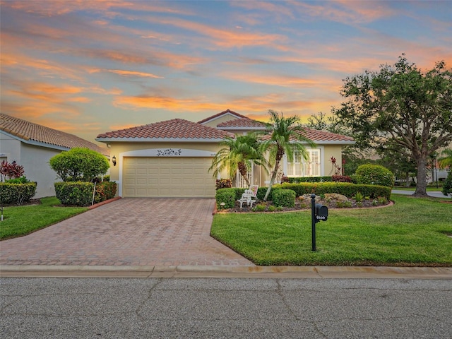 mediterranean / spanish-style home with a garage and a yard