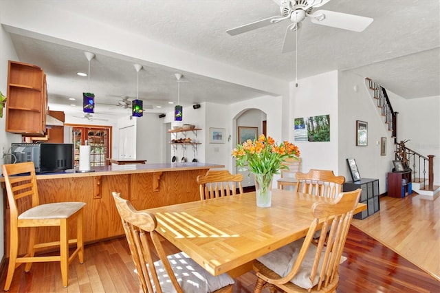 dining area with ceiling fan, hardwood / wood-style floors, and a textured ceiling