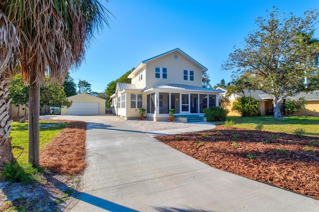 view of front of house featuring a garage, a sunroom, a front yard, and an outdoor structure