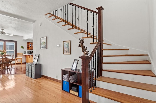 stairs featuring ceiling fan, hardwood / wood-style floors, and a textured ceiling