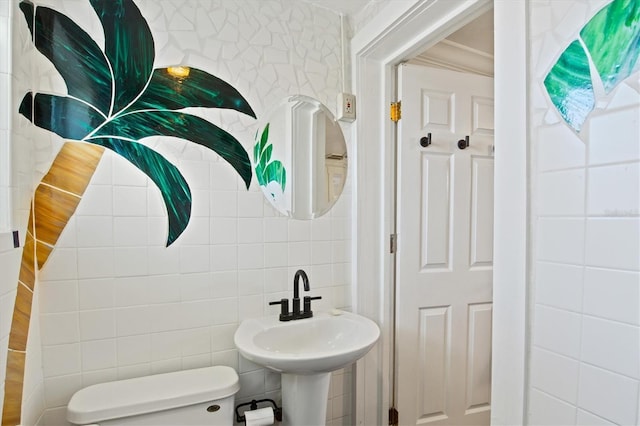 bathroom with sink, toilet, and tile walls