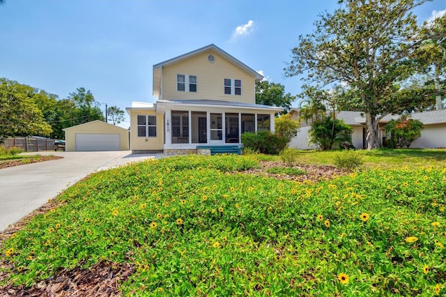 view of property with a front lawn, an outdoor structure, a garage, and a sunroom