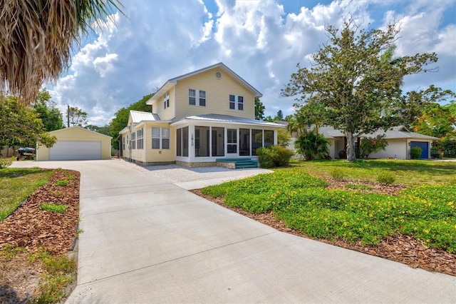 view of front of house featuring a garage, a sunroom, an outbuilding, and a front yard